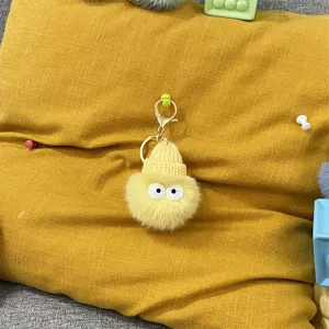 Close-up of a cute yellow plush soot sprite keychain with a knitted hat