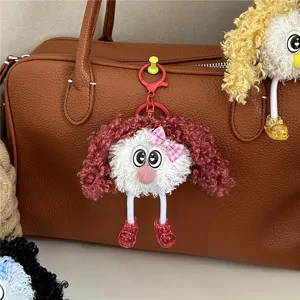 Detailed view of a cute curly-haired plush doll keychain hanging on a leather bag