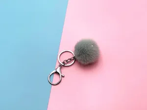 Detail of soft grey faux fur pom pom keychain with silver metal clasp and ring