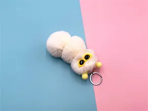Detail of a cute white plush caterpillar keychain with yellow sunglasses decoration.