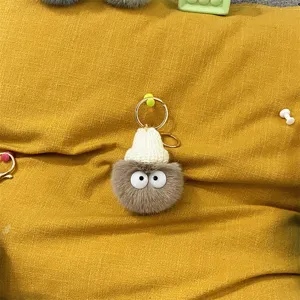 Detailed macro view of a fuzzy gray soot sprite keychain featuring a tiny white knitted hat.