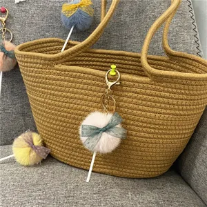 Detailed view of a cute plush lollipop keychain with a lace bow on a woven bag