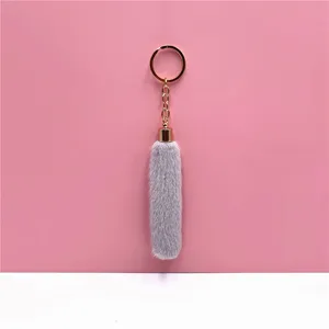 Close-up detail of a soft gray plush tassel keychain with a polished golden metal ring.