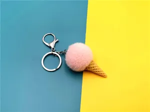 Close-up of a cute pink plush ice cream cone keychain on a vibrant blue and yellow background