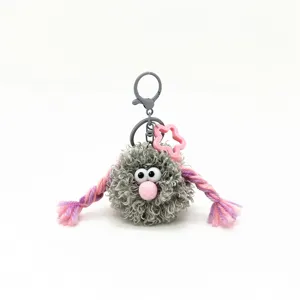 Close-up of a fuzzy gray monster keychain with pink braids and star charm accessory