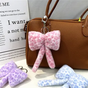 Close-up of cute leopard print plush bow bag charm attached to a brown handbag