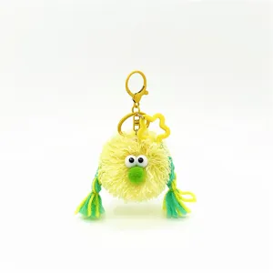 Detail view of cute yellow fuzzy plush doll keychain featuring green braided hair charms