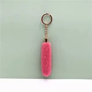 Detail showing soft pink plush fur texture on long gold metal keychain