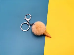 Close-up of cute plush ice cream cone keychain with soft peach pom-pom and metal ring