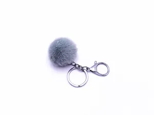Detail view of fluffy grey faux fur pom pom keychain with silver metal clasp ring