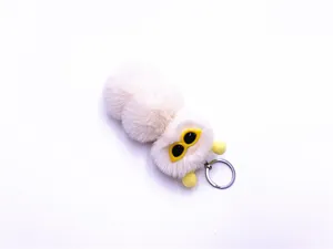 Macro view of cute white plush caterpillar keychain with yellow pom-pom details