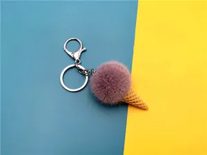 Close-up of plush ice cream cone keychain with a pink pom-pom on a blue and yellow backdrop.