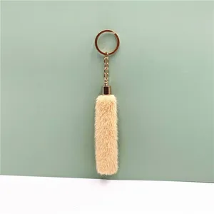 Detail of cute apricot plush tassel keychain with gold-tone ring for bags or car keys
