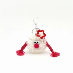 Close-up of a funny white plush monster keychain with pink braids and a red star
