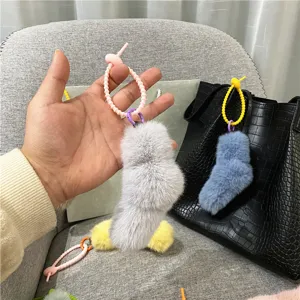 Close-up of cute plush sock charms in candy colors hanging on a stylish black leather bag