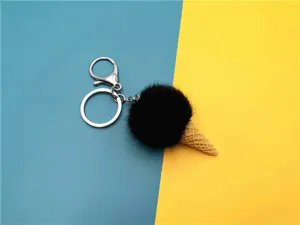Detailed view of plush black pom-pom ice cream cone keychain on bi-color background