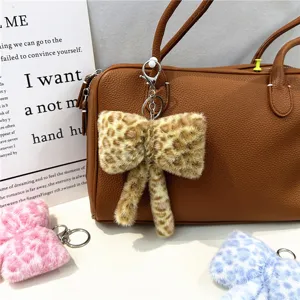 Detail view of stylish leopard print plush bow keychain charm hanging on a brown bag