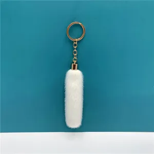 Close-up detail of a soft white plush furry tassel keychain with a elegant gold-finish metal ring