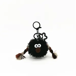Detailed view of an ugly-cute black plush bag charm with funny eyes and braided arms