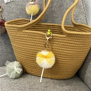 Close-up detail of a cute lollipop-shaped plush keychain with a yellow lace bow on a bag
