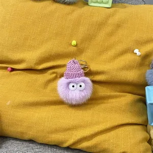 Detailed view of purple furry pom-pom keychain featuring a cute pink knitted hat
