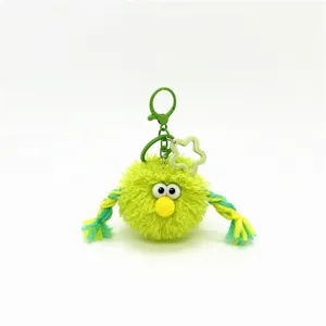 Detail showing the fluffy texture and braided rope arms of the green monster keychain.