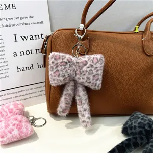 Detailed view of plush leopard print bow-knot keychain accessory on a brown bag