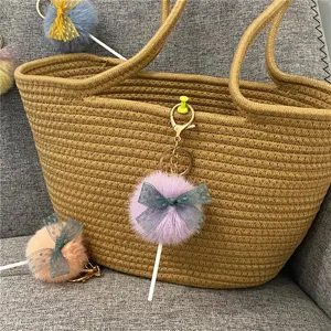 Detailed view of a cute purple pom-pom lollipop keychain with a lace bow on a bag.
