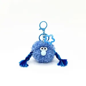 Detailed close-up of a blue fuzzy monster plush keychain with braids and large eyes.