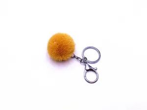 Close-up detail of a bright yellow fluffy pom-pom keychain with silver metal ring