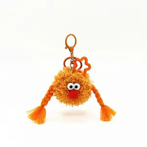 Detail view of an orange fuzzy monster keychain with cute braids and big eyes