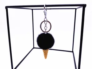 Close-up of black plush pom pom ice cream cone keychain on a black metal display