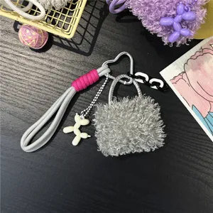 Close-up detail of a plush grey bag charm with heart carabiner and cute balloon dog charm
