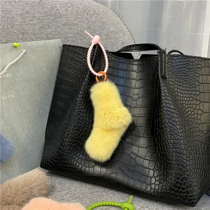 Cute yellow plush sock-shaped bag charm featuring a pink silicone twist knot strap detail
