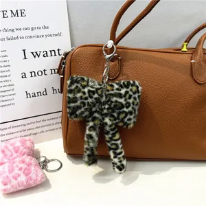 Close-up of leopard print fuzzy bow keychain charm on a brown leather bag