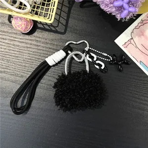 Detail of black plush bag charm with heart carabiner and balloon dog pendant