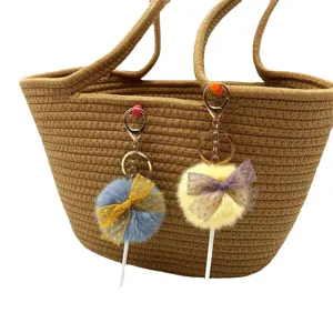 Adorable plush lollipop keychains with lace bows shown hanging on a woven brown tote bag