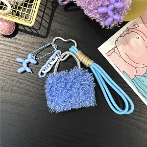 Close-up detail of blue fluffy handbag charm featuring a heart buckle and blue balloon dog