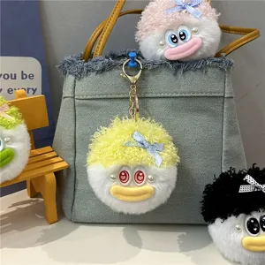Detailaufnahme von bunten, flauschigen Monster-Schlüsselanhängern an einer grauen Denim-Tasche