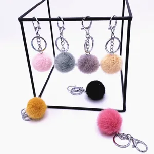 Colorful faux fur pom pom keychains with silver lobster clasps on a creative metal display stand