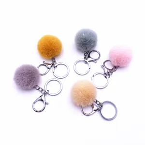 Set of five colorful plush pom pom keychains with silver hardware on white background