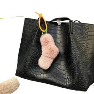 Cute pink plush sock charm with candy colored spiral strap attached to a black tote bag