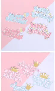 Close-up detail of pastel pink and blue Happy Birthday princess and prince cake toppers