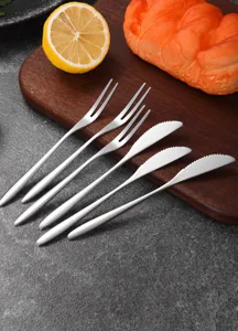 Detailed view of silver stainless steel fruit forks and cake knives on a wooden board
