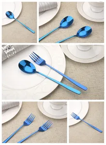 Detail view of modern blue plated stainless steel spoon and fork cutlery set on table.
