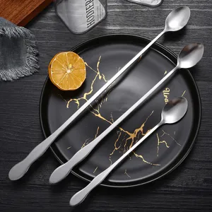 Set aus drei langstieligen Rührlöffeln aus Edelstahl mit Kürbisgriff auf schwarzer Platte.