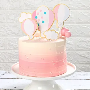 Primo piano di decorazioni per torta a mongolfiera e nuvola su una torta rosa chiaro
