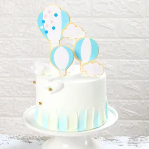 Dettaglio dei topper per torta a forma di mongolfiera e nuvole su torta bianca
