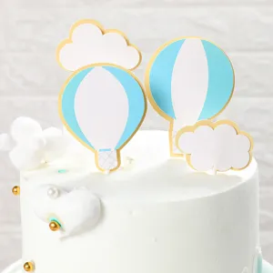Primo piano di topper per torta a forma di mongolfiera blu e nuvole bianche.