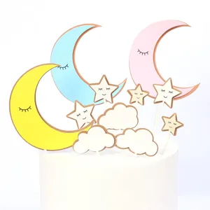 Set of moon, stars and clouds cake toppers inserted into a white birthday cake.